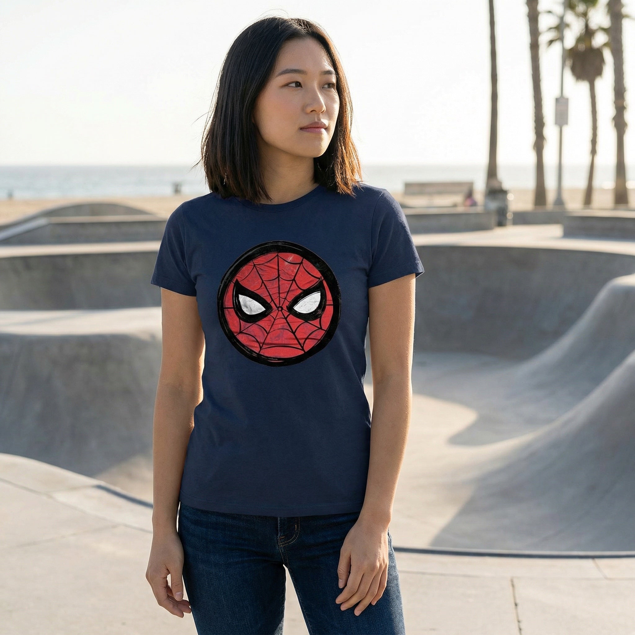 Woman wearing a navy blue t-shirt with a Spider-Man logo at a skate park.